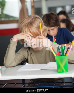 Bored Schoolboy Sitting At Desk In Classroom Banque D'Images