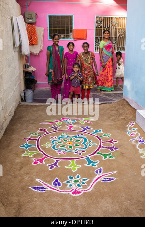 Les filles indiennes debout à côté d'une poudre de couleur festival Rangoli designs à Sankranti dans un village rural. L'Andhra Pradesh, Inde Banque D'Images