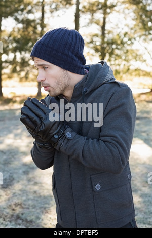 L'homme dans des vêtements chauds frissons tout en ayant une promenade en forêt Banque D'Images