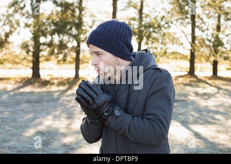 L'homme dans des vêtements chauds frissons tout en ayant une promenade en forêt Banque D'Images