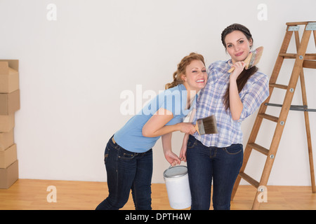 Friends holding peinture pinceaux et peut dans une nouvelle maison Banque D'Images