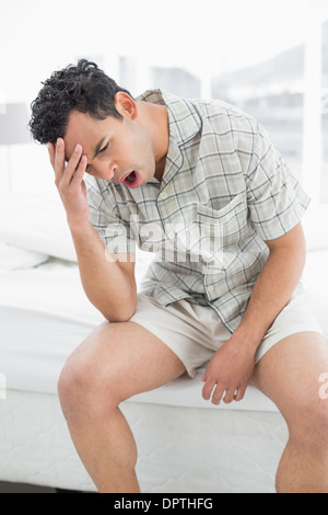 Jeune homme yawning in bed Banque D'Images