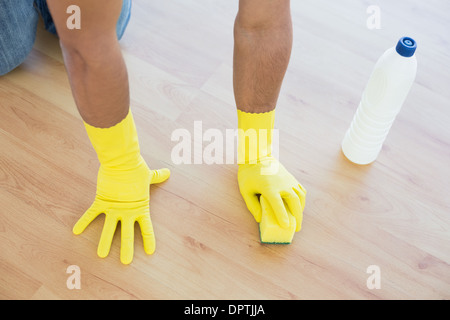 Les mains gantées jaunes avec éponge nettoyage du marbre Banque D'Images