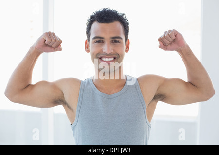 Fit young man flexing muscles in fitness studio Banque D'Images