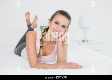 Smiling pretty young woman relaxing in bed Banque D'Images