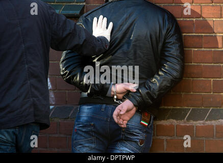 Haover, Allemagne. 10 janvier, 2014. Un officier de police en civil pousse un homme menotté contre le mur d'une maison en Haover, Allemagne, 10 janvier 2014. L'homme a été arrêté au cours d'une vérification de routine sur le trafic et menotté pour des raisons de sécurité. Photo : Julian Stratenschulte/dpa/Alamy Live News Banque D'Images