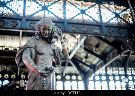 Statue de bronze du Mercado Central Santiago Chili / SANTIAGO, Chili — Une statue de bronze représentant une femme transportant de l'eau se dresse au centre du Mercado Central de Santiago, un monument historique de la capitale du Chili. Fondé en 1872, le Mercado Central est réputé pour sa vaste sélection de fruits de mer frais, reflétant l’importance des ressources maritimes dans la cuisine et la culture chiliennes. L'architecture distinctive du marché comprend un toit en fonte orné conçu par Edward Woods, tandis que l'architecte chilien Fermin Vivaceta a conçu les murs en maçonnerie néoclassique et la façade extérieure. Les néoclas Banque D'Images