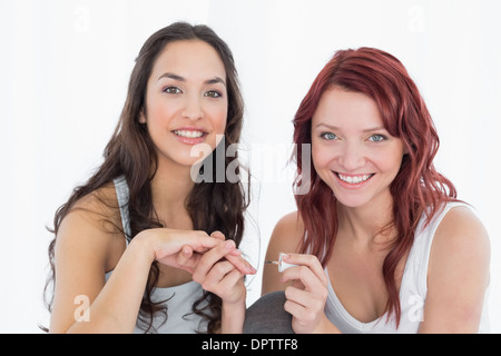 Smiling pretty young woman painting friends nails Banque D'Images