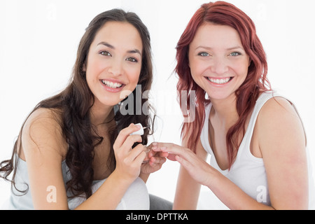 Smiling pretty young woman painting friends nails Banque D'Images