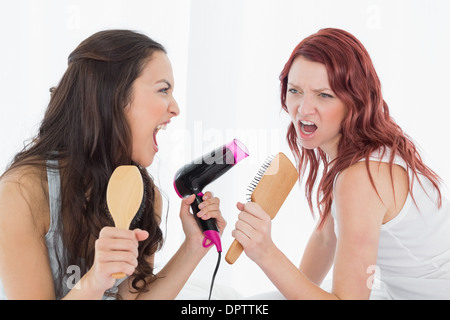 Amis féminins singing into hairbrush Banque D'Images