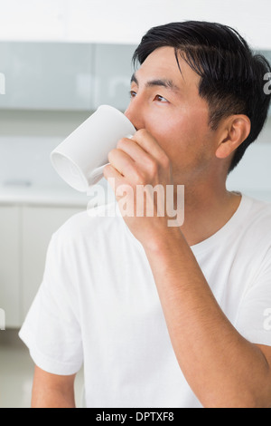 Homme sérieux de boire du café alors qu'il fait un pas dans la cuisine Banque D'Images