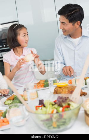 Père regardant petite fille manger des aliments dans la cuisine