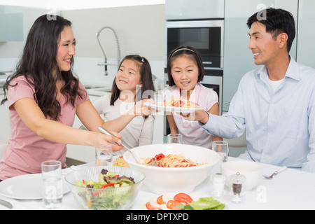 Femme heureuse de servir des aliments pour la famille dans la cuisine Banque D'Images