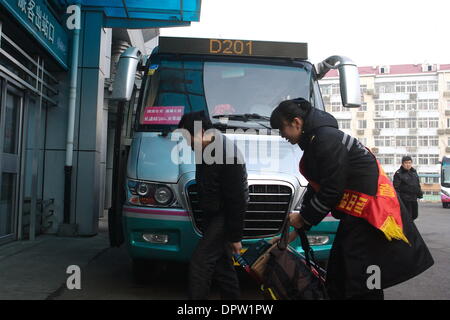 Qingdao, Chine, la province de Shandong. 16 janvier, 2014. Une aide bénévole un passager transporter bagages au Qingdao long-distance bus station à Qingdao, province de Shandong en Chine orientale, le 16 janvier 2014. La cérémonie d'ouverture de service bénévole activité nommée "voyage plein d'Amour', qui a été conjointement organisé par le ministère des Transports, ministère de la Sécurité publique, l'Administration de l'état de la sécurité au travail et Fédération des syndicats de Chine, a été organisé à nouveau à la station jeudi après sa première apparition en 1995. © Yin Xubao/Xinhua/Alamy Live News Banque D'Images