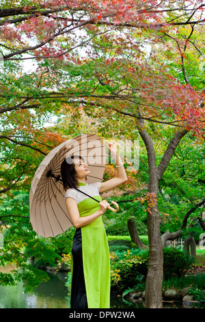 Jeune femme tenant un parasol sous des feuilles d'automne Banque D'Images