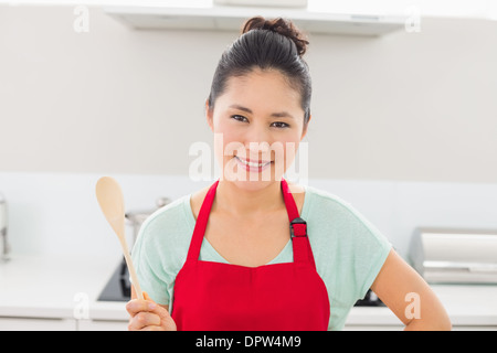 Femme en tablier rouge avec une cuillère en bois dans la cuisine Banque D'Images