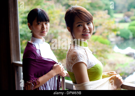 Deux jeunes femmes dans la traditionnelle vietnamienne Ao Dai robe souriant à l'appareil photo du côté. Banque D'Images