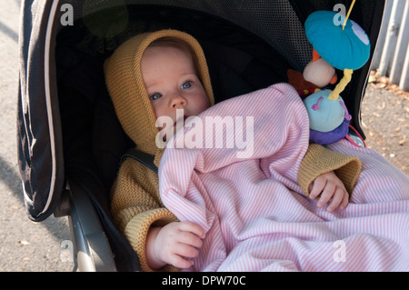 Bébé fille allongé dans son bébé regardant surpris Banque D'Images