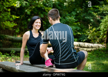 Jeune homme massage donne de veau à smiling woman après le jogging Banque D'Images