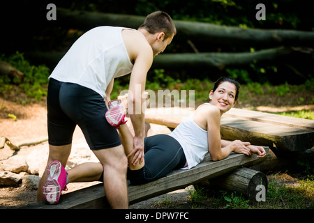 Massage homme donne de veau à jeune femme après le jogging Banque D'Images