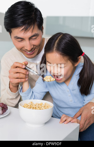 Père avec sa jeune fille ayant les céréales dans la cuisine Banque D'Images