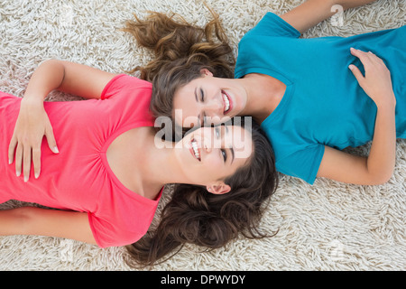 High angle view of two young female friends lying on rug Banque D'Images