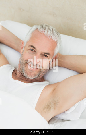 Portrait of a smiling young man resting in bed Banque D'Images