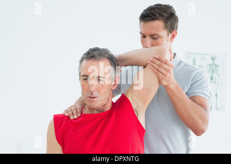 Physiothérapeute mâle mature étirer un bras mans Banque D'Images