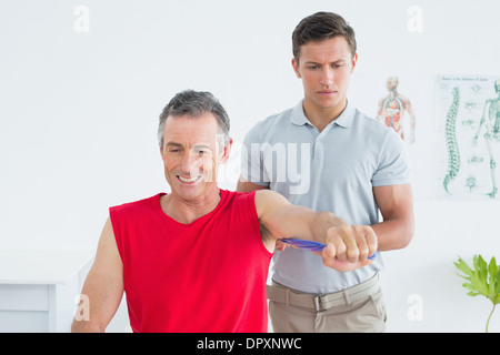 Physiotherapist examining a smiling young mans arm Banque D'Images