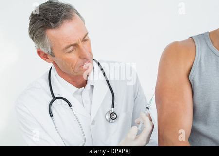 Médecin homme l'injection d'un bras de patients Banque D'Images