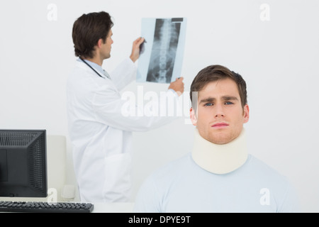 Patient en col chirurgical avec doctor examining x-ray derrière la colonne vertébrale Banque D'Images