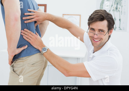 Portrait of a physiotherapist examining mans retour Banque D'Images