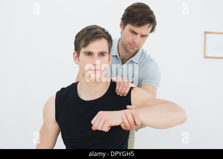 Un jeune mâle physiotherapist examining mans arm Banque D'Images