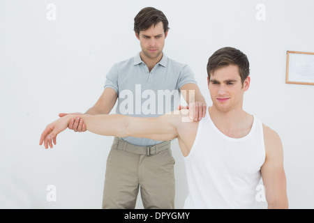Un jeune mâle physiotherapist examining mans arm Banque D'Images