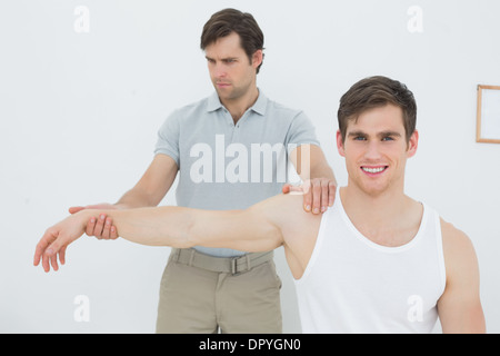 Un jeune mâle physiotherapist examining mans arm Banque D'Images