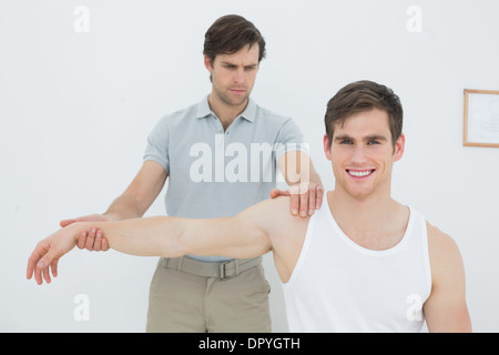 Un jeune mâle physiotherapist examining mans arm Banque D'Images