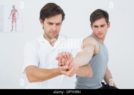 Un jeune mâle physiotherapist examining mans hand Banque D'Images