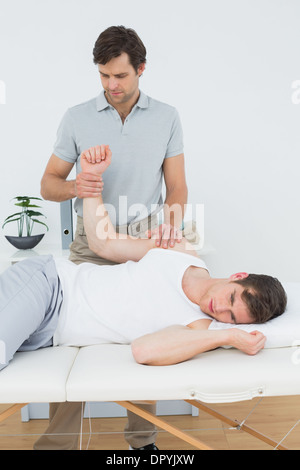 Un jeune mâle physiotherapist examining mans hand Banque D'Images