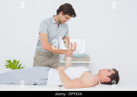 Un jeune mâle physiotherapist examining mans poignet Banque D'Images