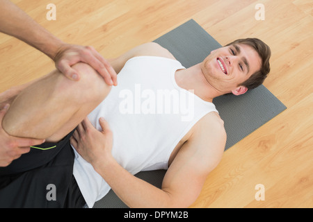 L'examen d'un thérapeute physique smiling young mans leg Banque D'Images