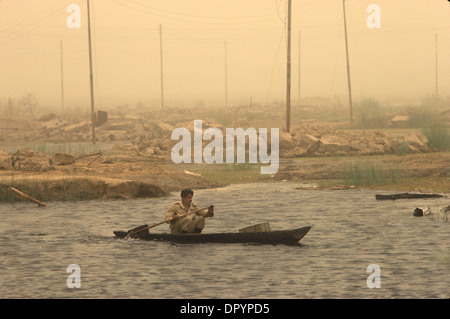 Iran guerre en Irak également connue sous le nom de première Guerre du Golfe persique ou Guerre du Golfe. 1984 Soldat se remettant de la récente bataille en canoë parmi les dévastations de la guerre. Les marais mésopotamiens, une tempête de sable dans les airs. Près de Basra Sud de l'Irak. HOMER SYKES des années 1980 Banque D'Images