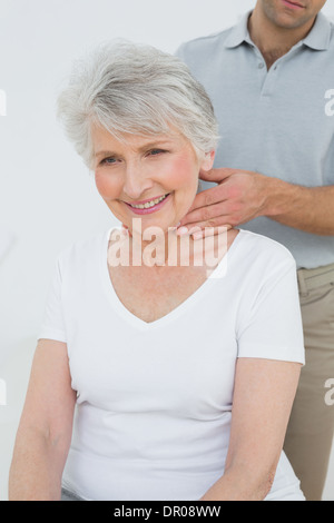 Physiothérapeute mâle le massage du cou d'une femme senior Banque D'Images