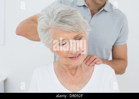 Physiothérapeute mâle le massage du cou d'une femme senior Banque D'Images