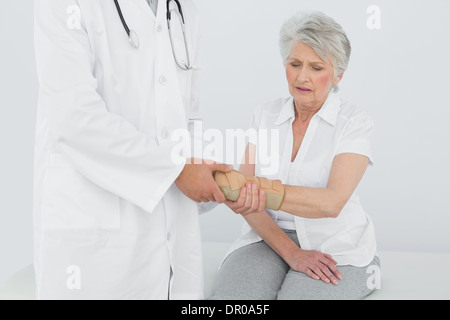 Homme physiotherapist examining a senior woman's wrist Banque D'Images