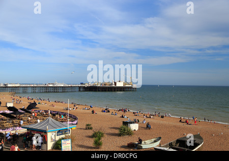 Se détendre sur la plage de galets, à côté de la jetée de Brighton qui a des activités de loisirs, dans la ville de Brighton, East Sussex, Royaume-Uni. Banque D'Images