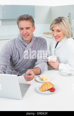 Dans deux peignoirs using laptop in kitchen Banque D'Images