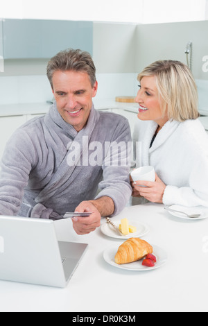 Dans deux peignoirs using laptop in kitchen Banque D'Images