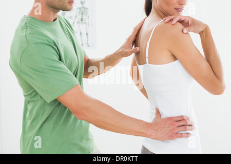 Physiotherapist examining woman's back in medical office Banque D'Images