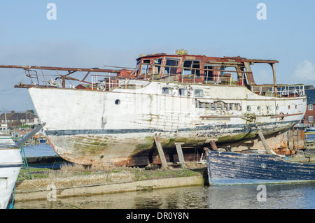 Un bateau abandonné en décomposition en bois sorti de l'eau par une rivière. Banque D'Images