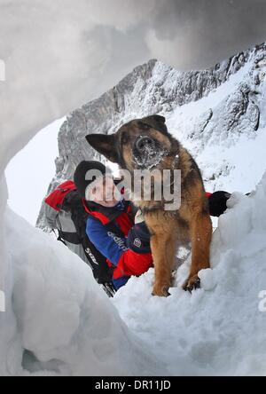 Garmisch-Partenkirchen, Allemagne. 17 Jan, 2014. Avalanch entraîneur de chien Franz Schreiber s'agenouille à côté de rescue dog Aico comme il creuse des survivants lors d'un exercice d'entraînement dans les Alpes, près de Garmisch-Partenkirchen, Allemagne, 17 janvier 2014. Dresseurs de chiens de sauvetage en montagne sont la formation de leurs chiens de recherche de victimes d'avalanche pour une semaine. Photo : Karl Josef OPIM/dpa/Alamy Live News Banque D'Images